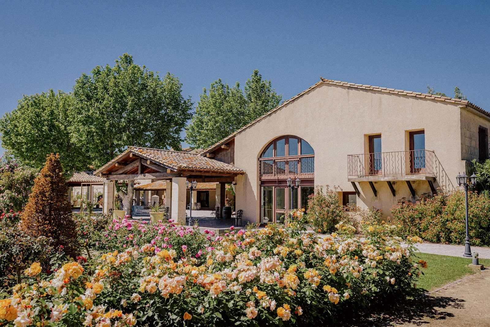 Façade du Domaine Mas Saint Gabriel entourée de rosiers en fleurs, lieu de mariage de charme dans l'Hérault