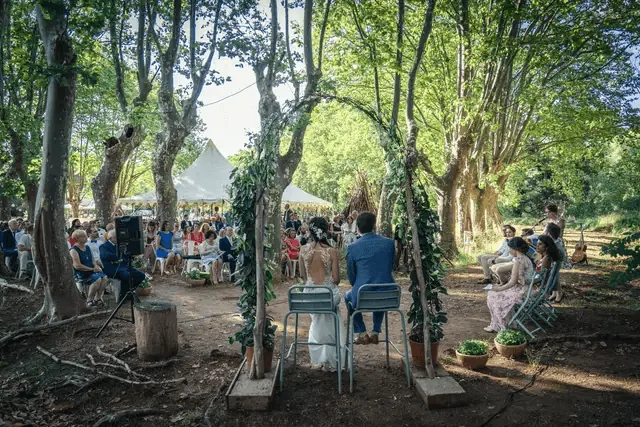 Cérémonie laïque sous les arbres, arche végétale, mariés, invités, tente de réception, ambiance champêtre Domaine Pech Laurier Quarante mariage Hérault Occitanie