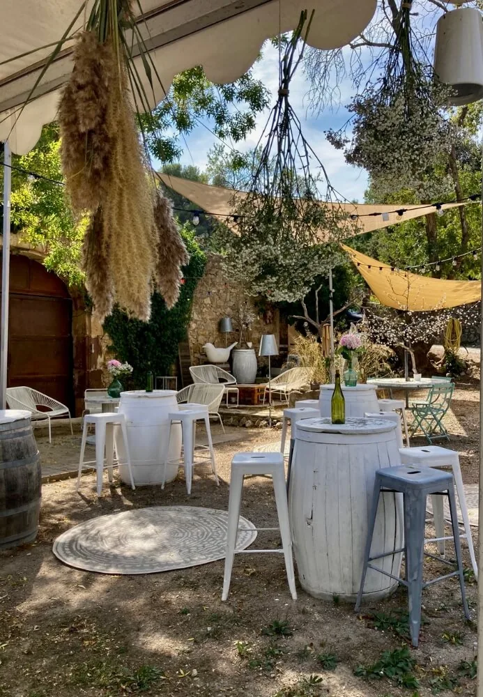 Jardin extérieur aménagé, tables tonneaux, chaises, décorations florales, ambiance festive, Domaine Pech Laurier Quarante mariage Hérault Occitanie
