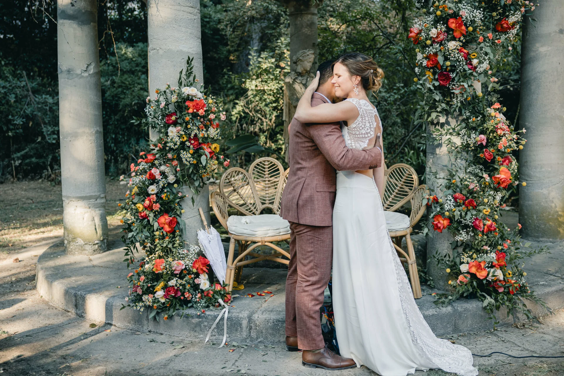 Mariés sous portique de colonnes fleuries au Domaine Le Petit Malherbes, mariage en Hérault