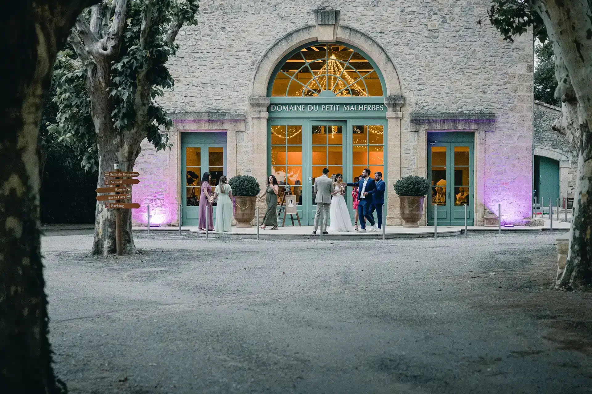 Soirée de mariage au Domaine du Petit Malherbes dans l'Hérault, façade illuminée et mariés devant l'entrée