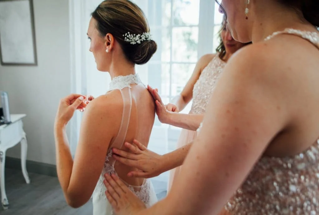 Habillage de la mariée par ses demoiselles d'honneur dans une chambre du Domaine Saint Hilaire en Hérault