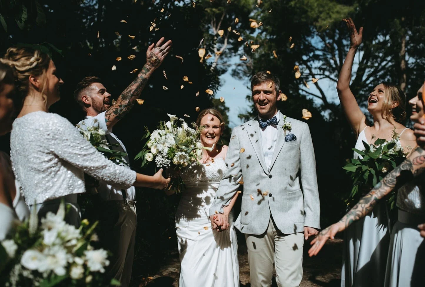 Couple de mariés acclamé avec lancer de pétales dorés à la sortie de cérémonie au Domaine Saint Hilaire en Hérault