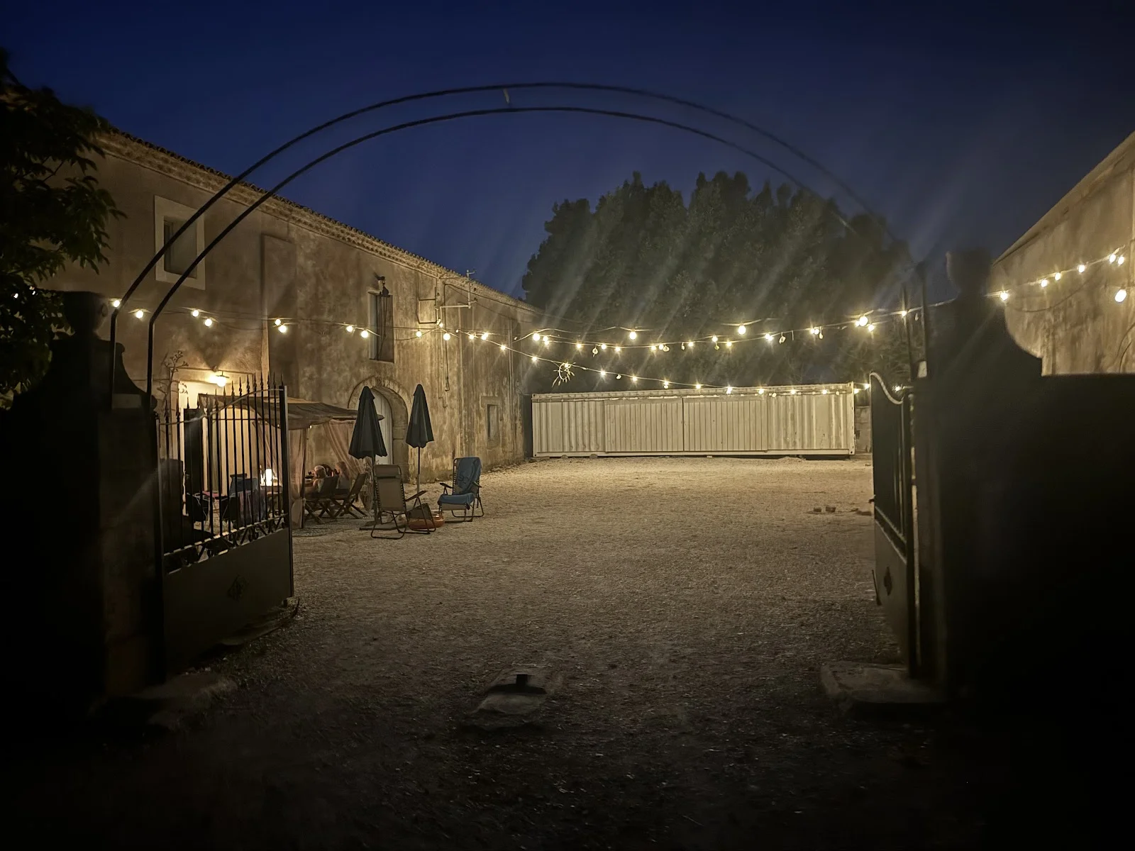 Cour du Domaine Saint Paul le Marseillais illuminée de guirlandes lumineuses la nuit, cadre authentique pour mariage en Hérault