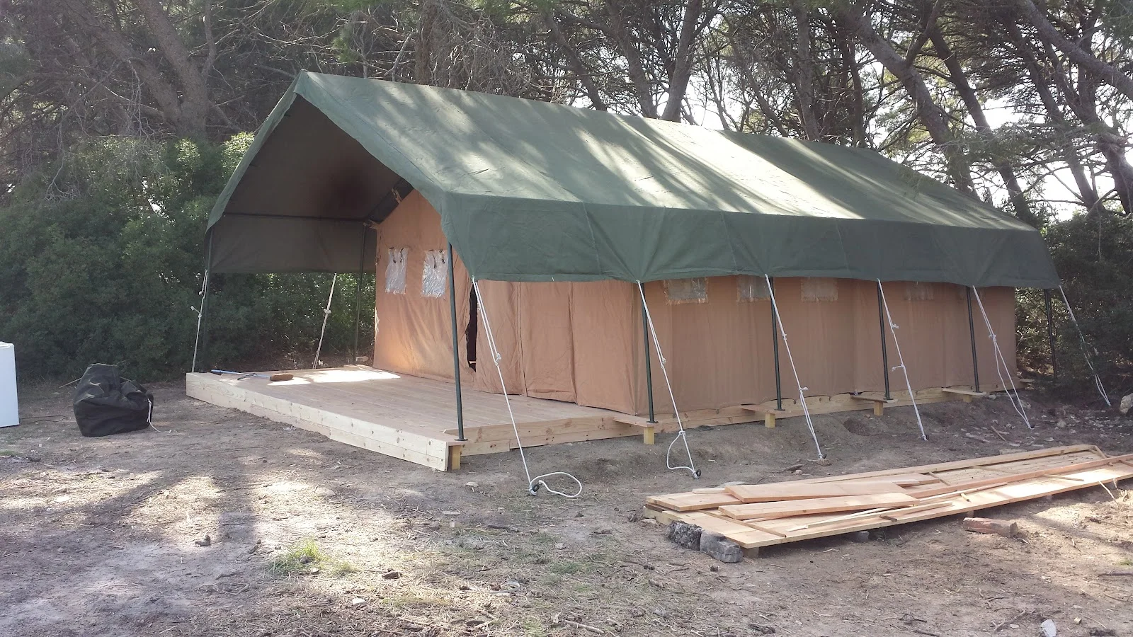 Installation d'une grande tente de glamping sur plateforme bois dans les pins au Domaine Saint Paul le Marseillais, Hérault