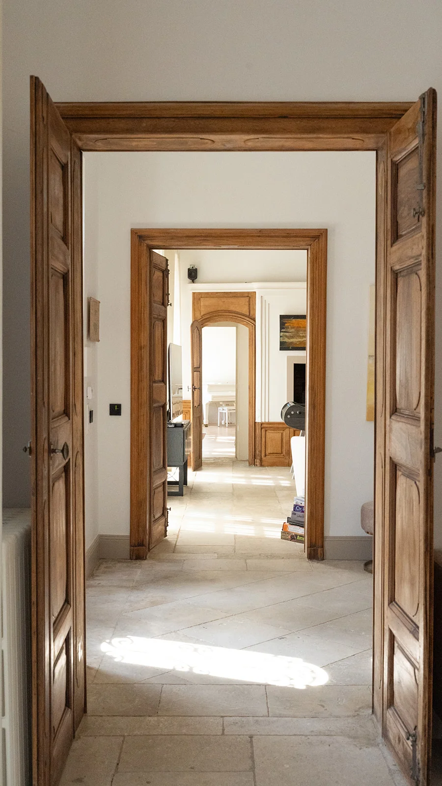 Couloir intérieur La Bastide Castella avec portes en bois massif sculpté et sol en pierre - domaine mariage Hérault