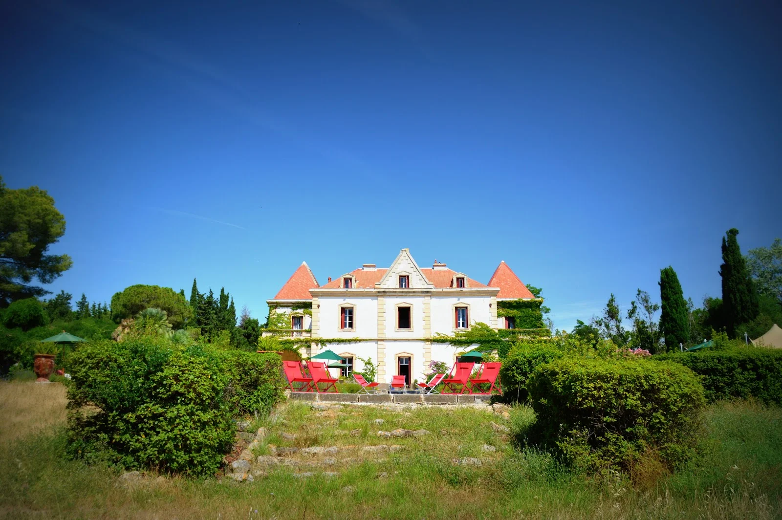 Façade du manoir La Bellonette lieu de mariage en Hérault avec toits rouges et terrasse ensoleillée