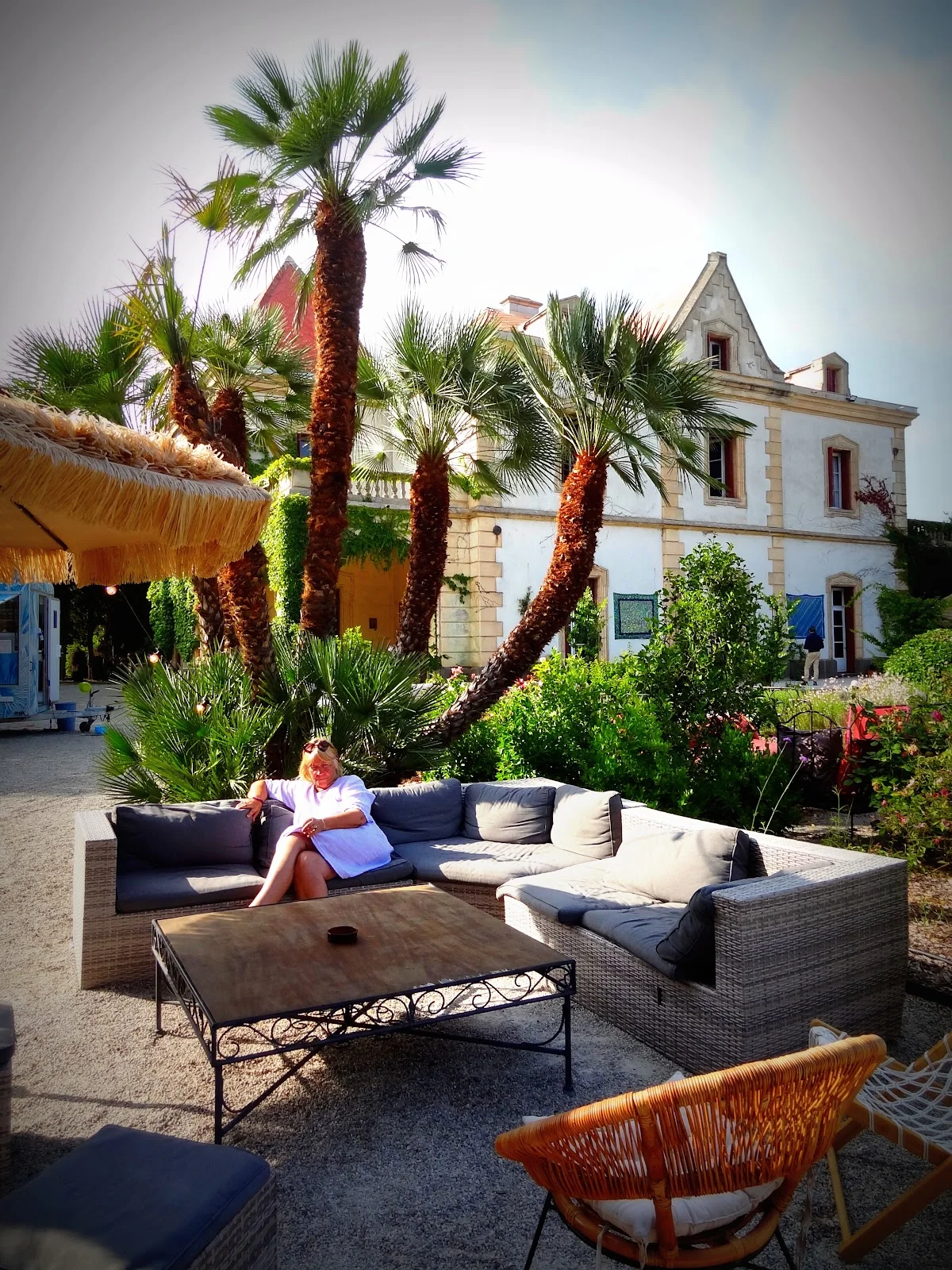 Espace lounge extérieur avec palmiers et canapés du domaine La Bellonette en Hérault pour mariage