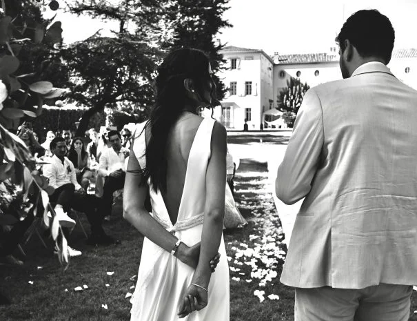 Couple de mariés remontant l'allée de cérémonie en plein air à La Trésorière, photo noir et blanc, pétales au sol, Hérault