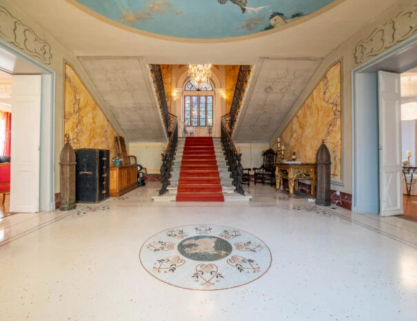 Hall d'entrée monumental de La Trésorière avec escalier en marbre, tapis rouge et peintures Belle Époque, domaine mariage Hérault