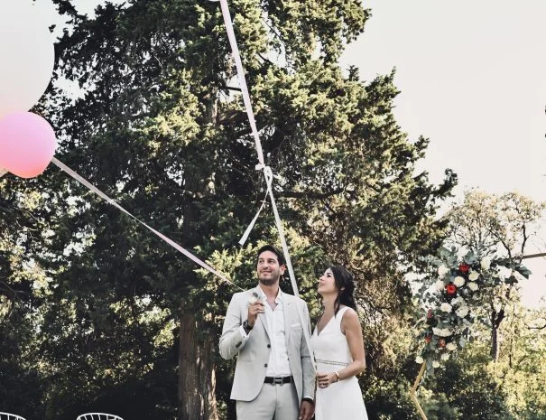 Couple de mariés avec ballon rose lors de la cérémonie extérieure dans le parc de La Trésorière, mariage Hérault