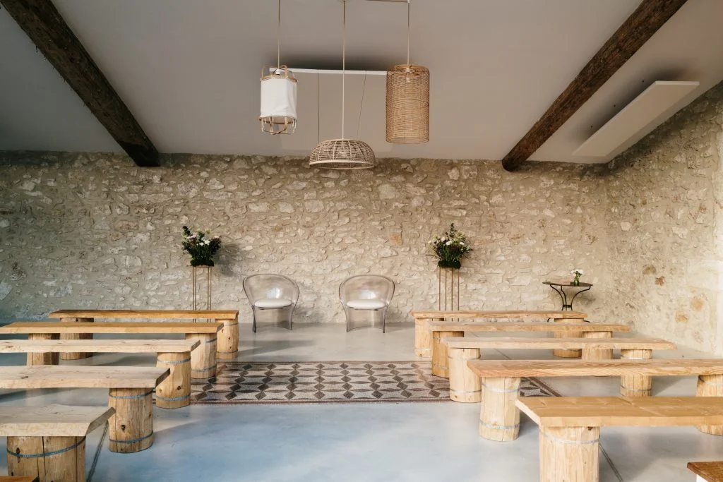 Salle intérieure rustique chic du Domaine La Trésorière avec murs en pierre et poutres, mariage Hérault