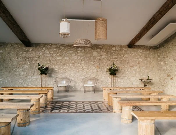 Salle de cérémonie laïque La Trésorière Hérault avec murs en pierre, bancs bois et suspensions en rotin