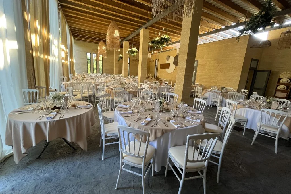 Salle de réception La Trésorière dressée pour un mariage, tables rondes et décor bohème chic en Hérault