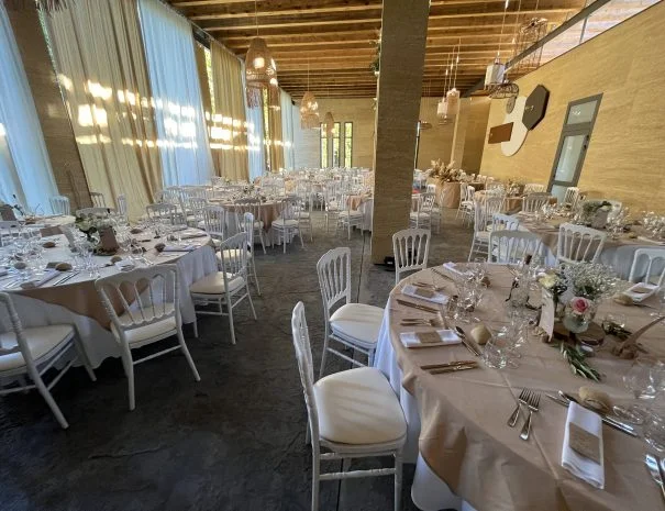 Salle de réception tables rondes dressées La Trésorière Hérault avec chaises Napoléon blanches et colonnes en pierre