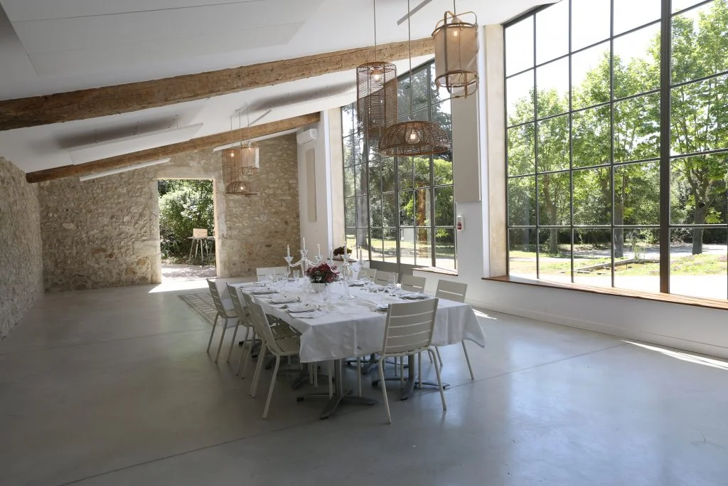 Salle lumineuse de La Trésorière avec grandes baies vitrées sur le parc, table dressée pour mariage en Hérault