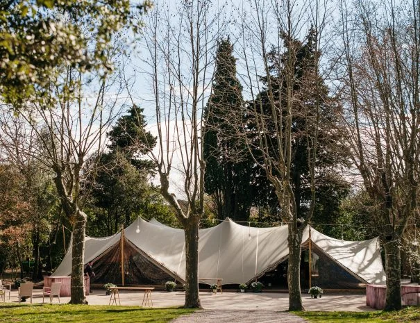 Tente stretch blanche installée dans le parc arboré de La Trésorière pour un mariage en plein air dans l'Hérault