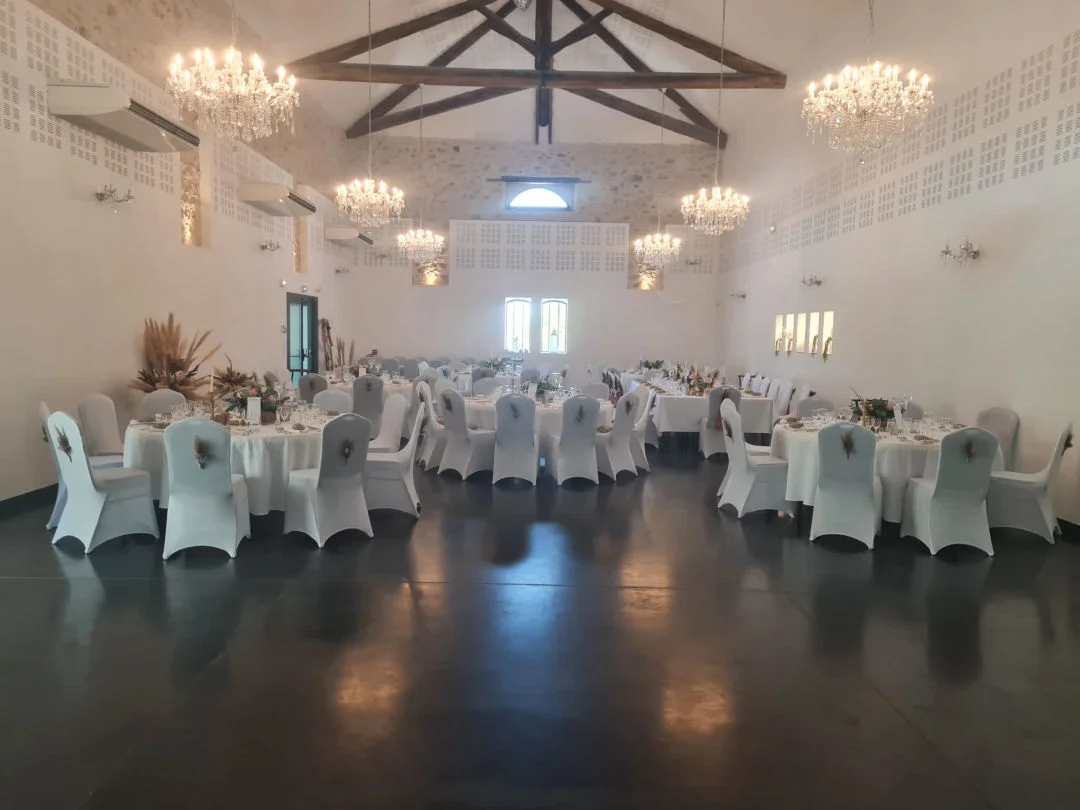 Grande salle de réception du Mas de Laux en Hérault avec lustres en cristal et tables de mariage