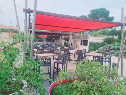 Terrasse cocktail du Mas de Laux avec voile rouge et mobilier extérieur, mariage en Hérault