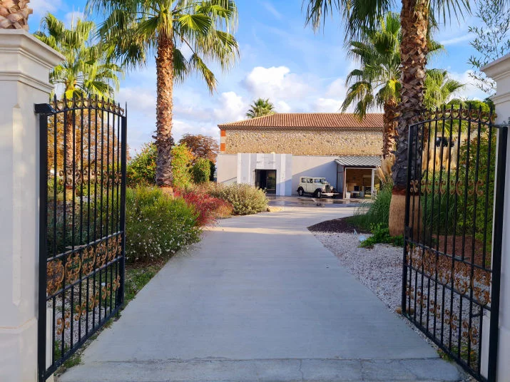 Vue extérieure du Mas de Laux depuis le portail, allée et mas en pierre, lieu de mariage en Hérault