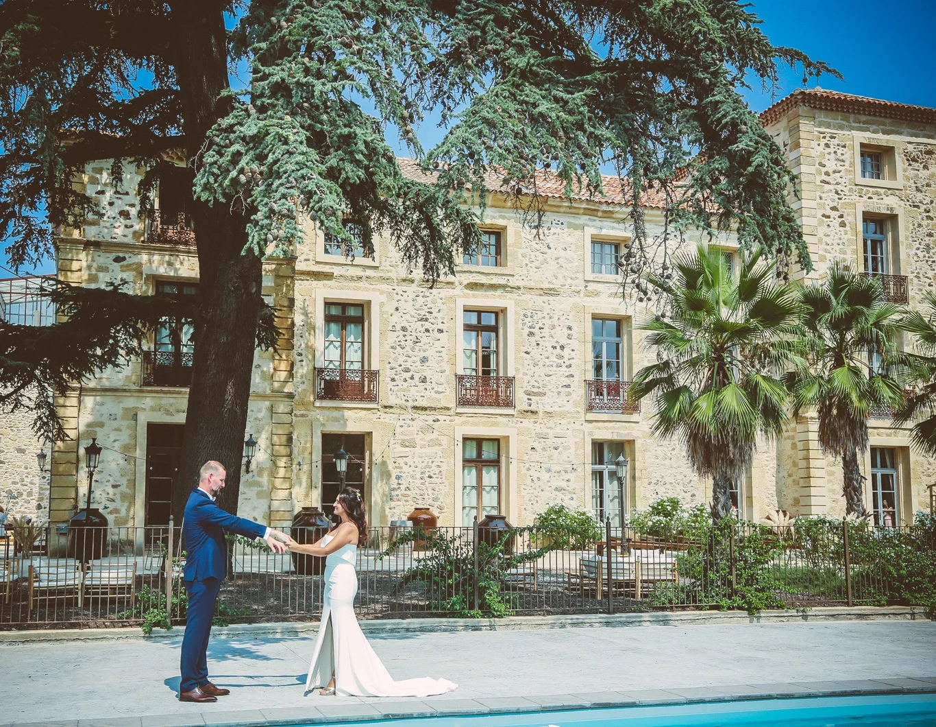 Couple de mariés devant la façade en pierre du domaine Les Castans pour un mariage dans l'Hérault