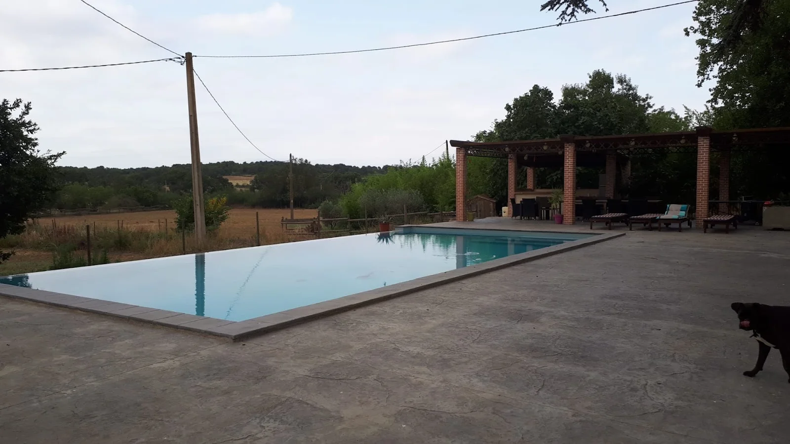 Piscine à débordement du domaine Les Castans avec vue sur la campagne de l'Hérault et pergola en brique
