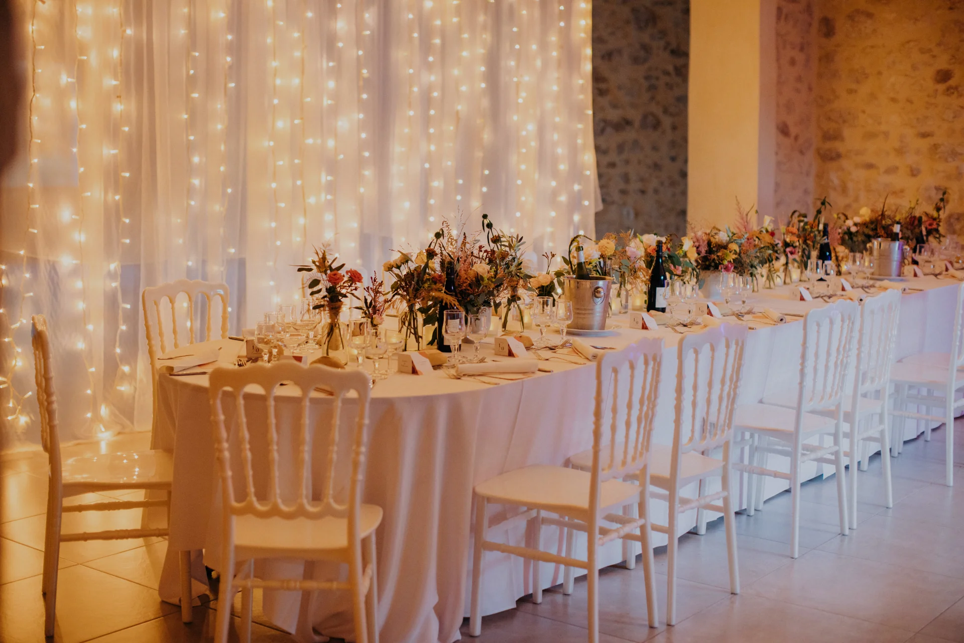Salle de réception mariage aux Charmes de Bailly Hérault avec guirlandes lumineuses et table banquet fleurie