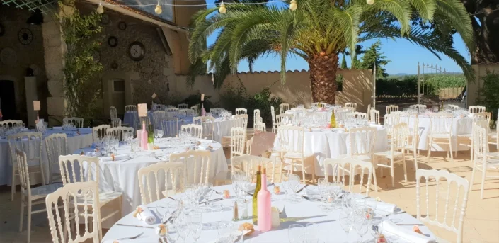 Terrasse extérieure dressée pour un repas de mariage au domaine Les Charmes de Bailly en Hérault, tables blanches sous le soleil