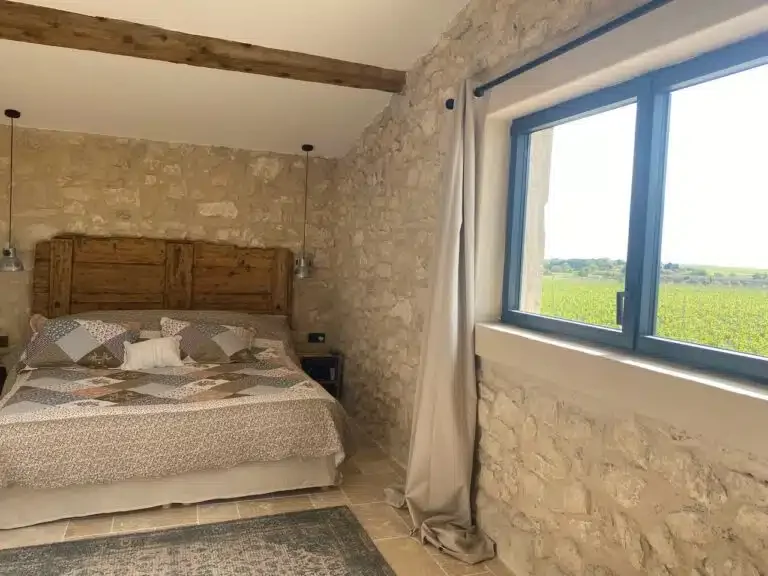 Chambre avec lit double, mur en pierre et vue sur les vignes - Les Granges Saint Paul, domaine mariage Hérault