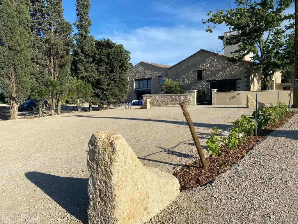 Entrée et parking du domaine Les Granges Saint-Paul de jour, bâtiments en pierre et cyprès, Hérault