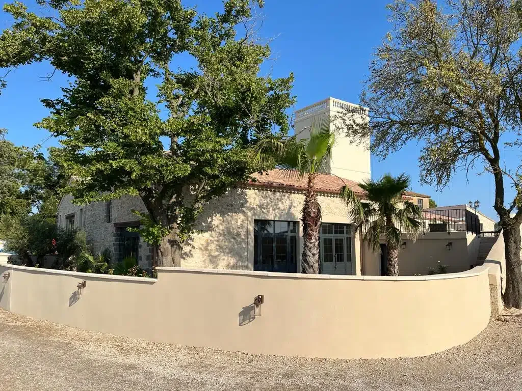 Façade des Granges Saint-Paul avec mur arrondi et palmiers de jour, lieu mariage Hérault
