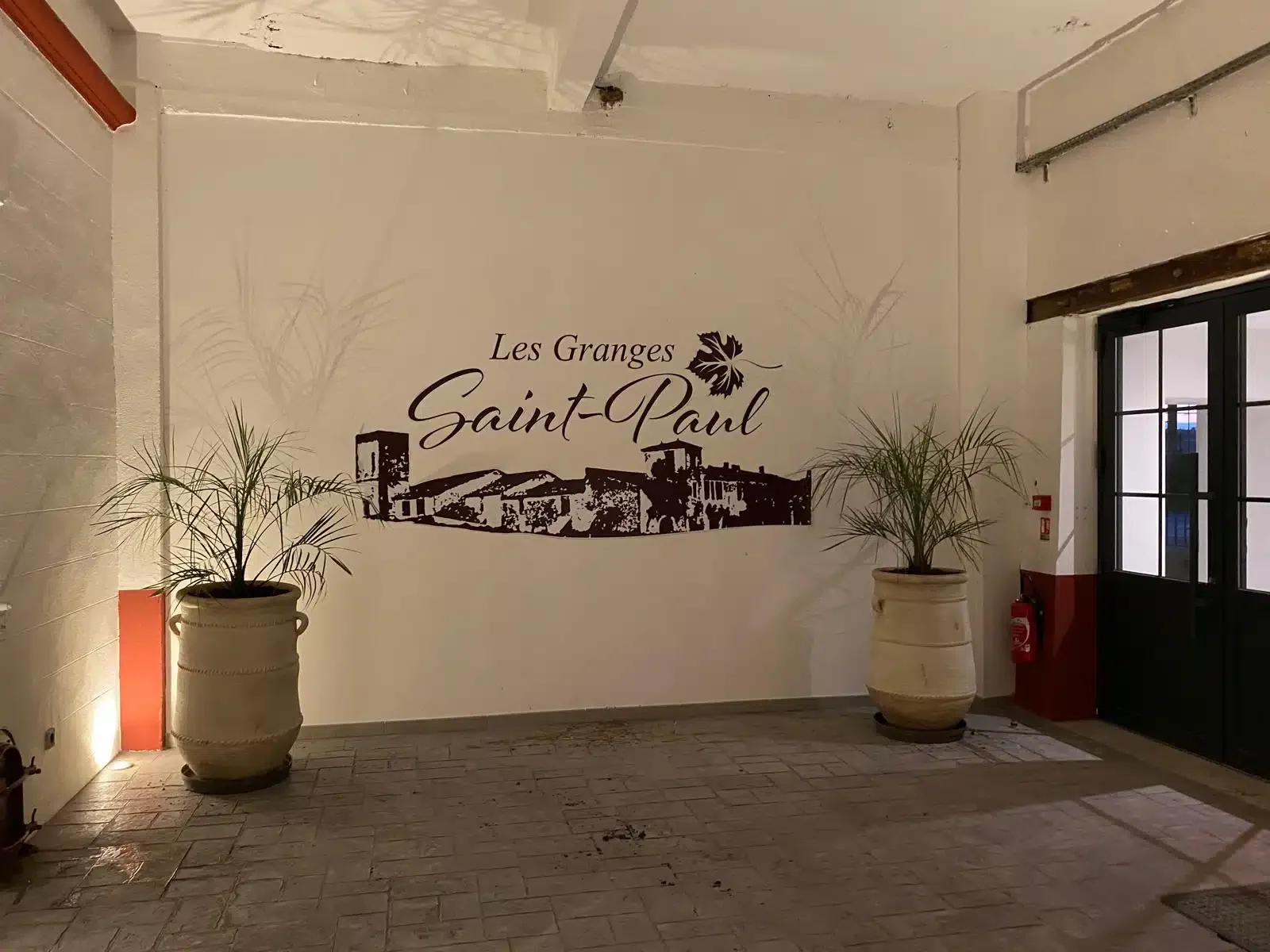 Logo mural Les Granges Saint-Paul dans le hall d'entrée avec jarres en terre cuite, domaine mariage Hérault