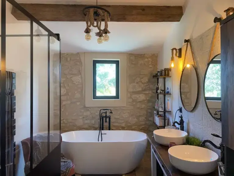 Salle de bain avec baignoire îlot et double vasque sur mur en pierre - Les Granges Saint Paul Hérault