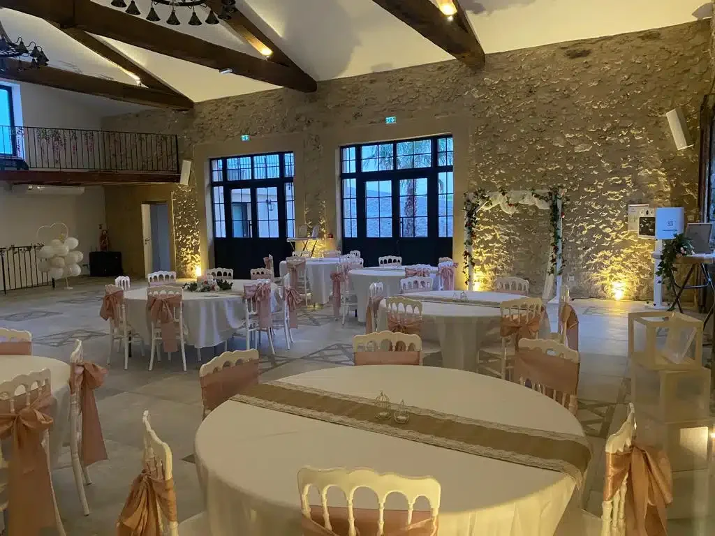 Salle de réception Les Granges Saint-Paul décorée pour un mariage avec tables rondes et chaises Napoléon roses, Hérault