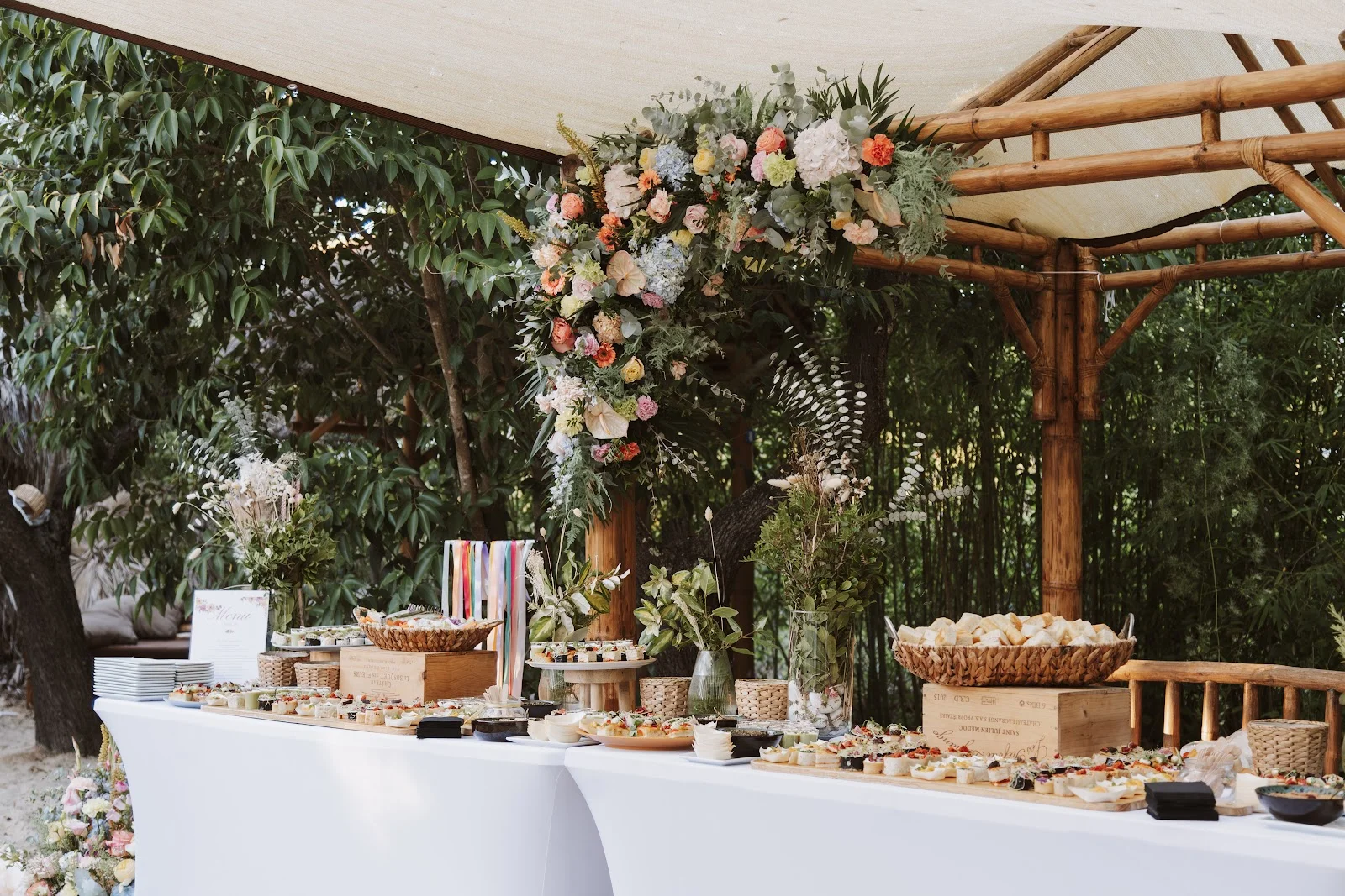 Table de cocktail fleurie à L'Impensable Aniane, buffet de verrines et amuse-bouches sous pergola bambou, mariage Hérault