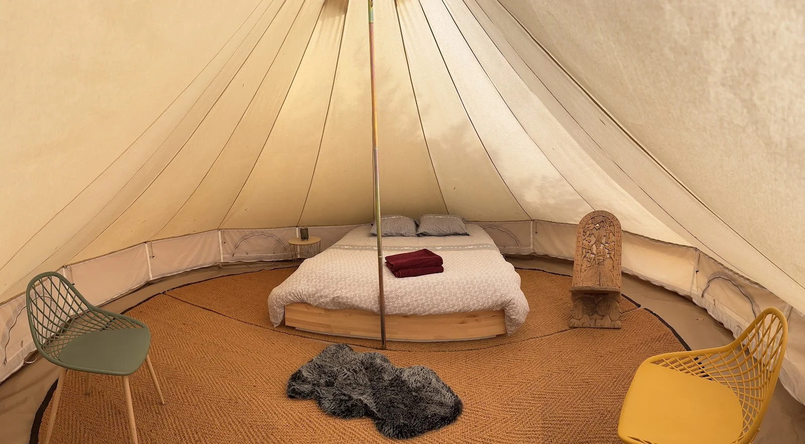 Intérieur bell tent glamping de L'Impensable Aniane, lit double sur estrade bois et décoration ethnique, mariage Hérault