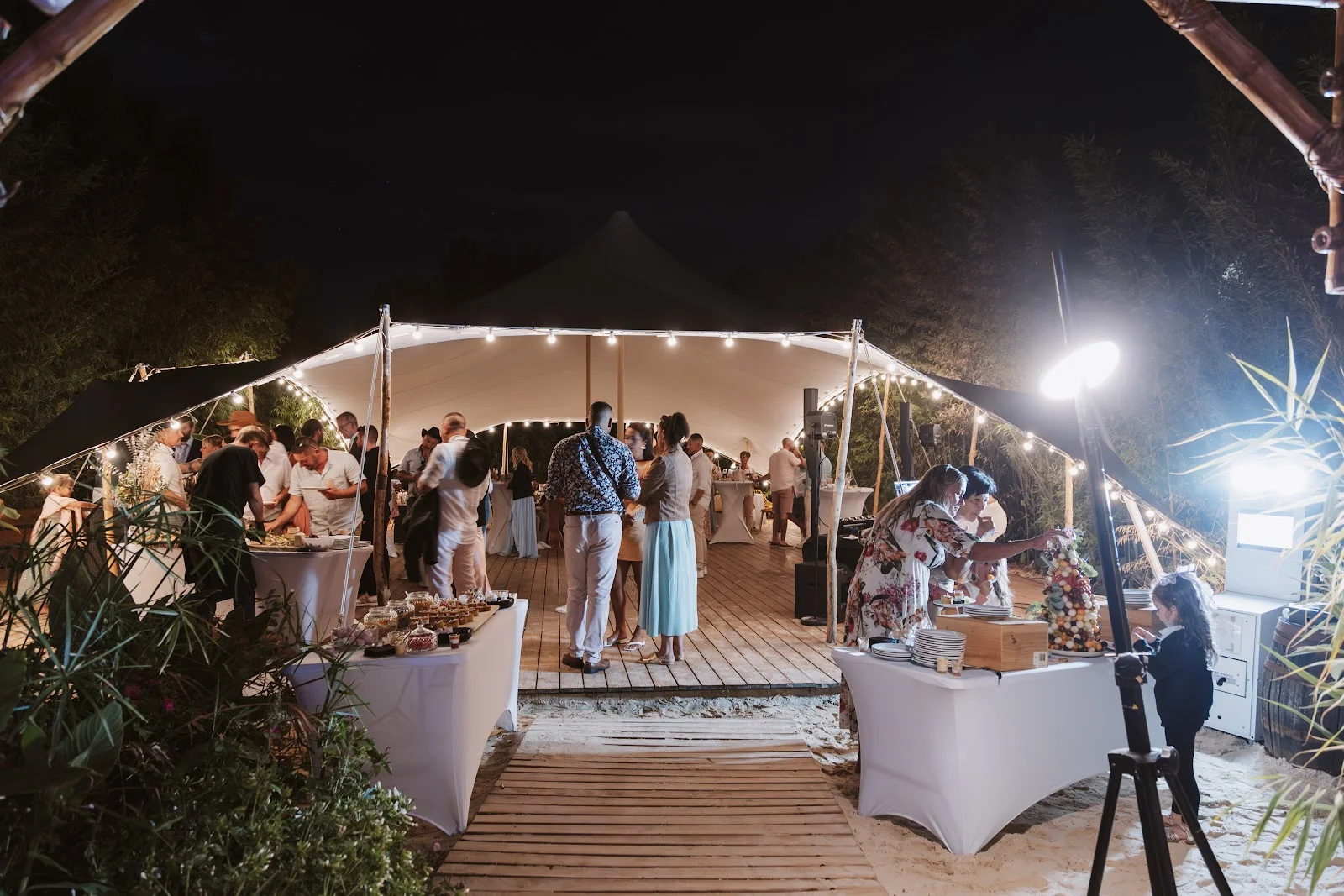 Tente de réception blanche illuminée de nuit à L'Impensable Aniane avec invités et photobooth, mariage Hérault