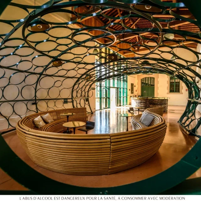 Espace lounge design de la Maison Noilly Prat à Marseillan avec installation circulaire en métal vert et banquette ronde, Hérault