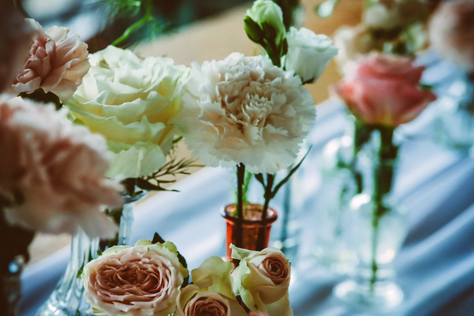 Décoration florale de mariage au Mas Aubrilha en Hérault avec œillets blancs et roses champêtres en vases