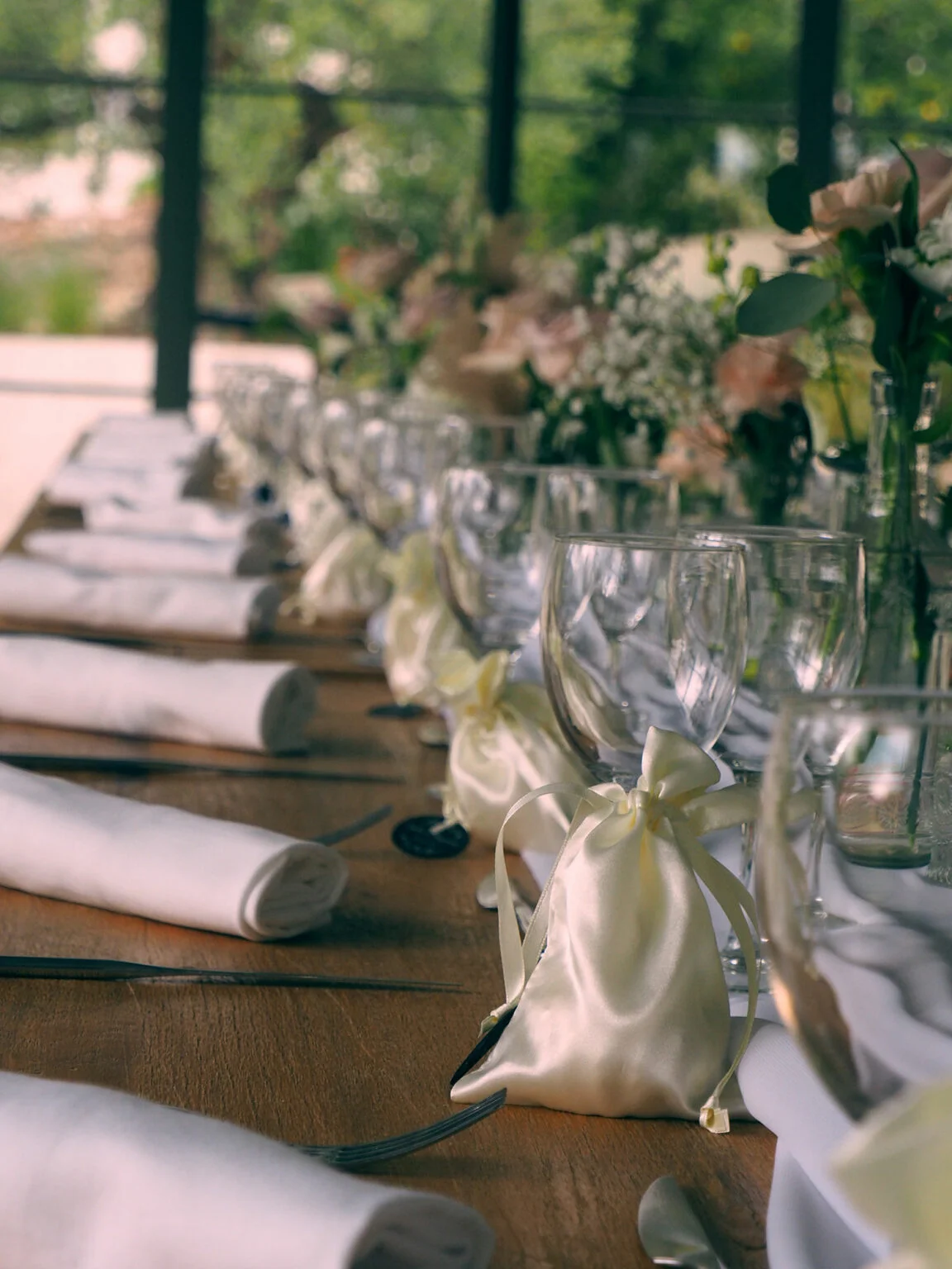 Détail décoration table mariage Mas Aubrilha : pochettes satin ivoire, verres cristal et fleurs, domaine Hérault