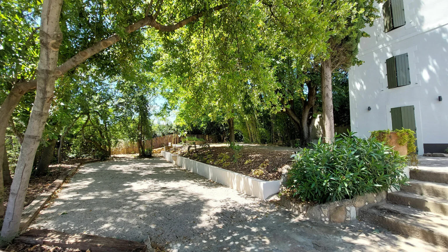 Façade blanche du Mas Aubrilha avec volets verts et allée ombragée, domaine mariage Hérault
