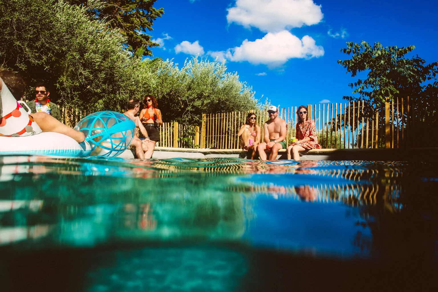 Piscine party festive au bord de la piscine du Mas Aubrilha, groupe d'amis sous le soleil de l'Hérault lors d'un mariage