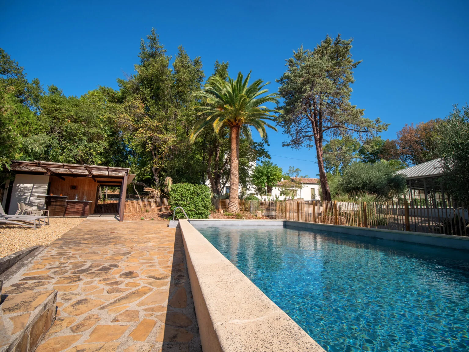Piscine house du Mas Aubrilha avec pergola naturelle, bar extérieur en bois et terrasse en pierre, espace détente mariage Hérault