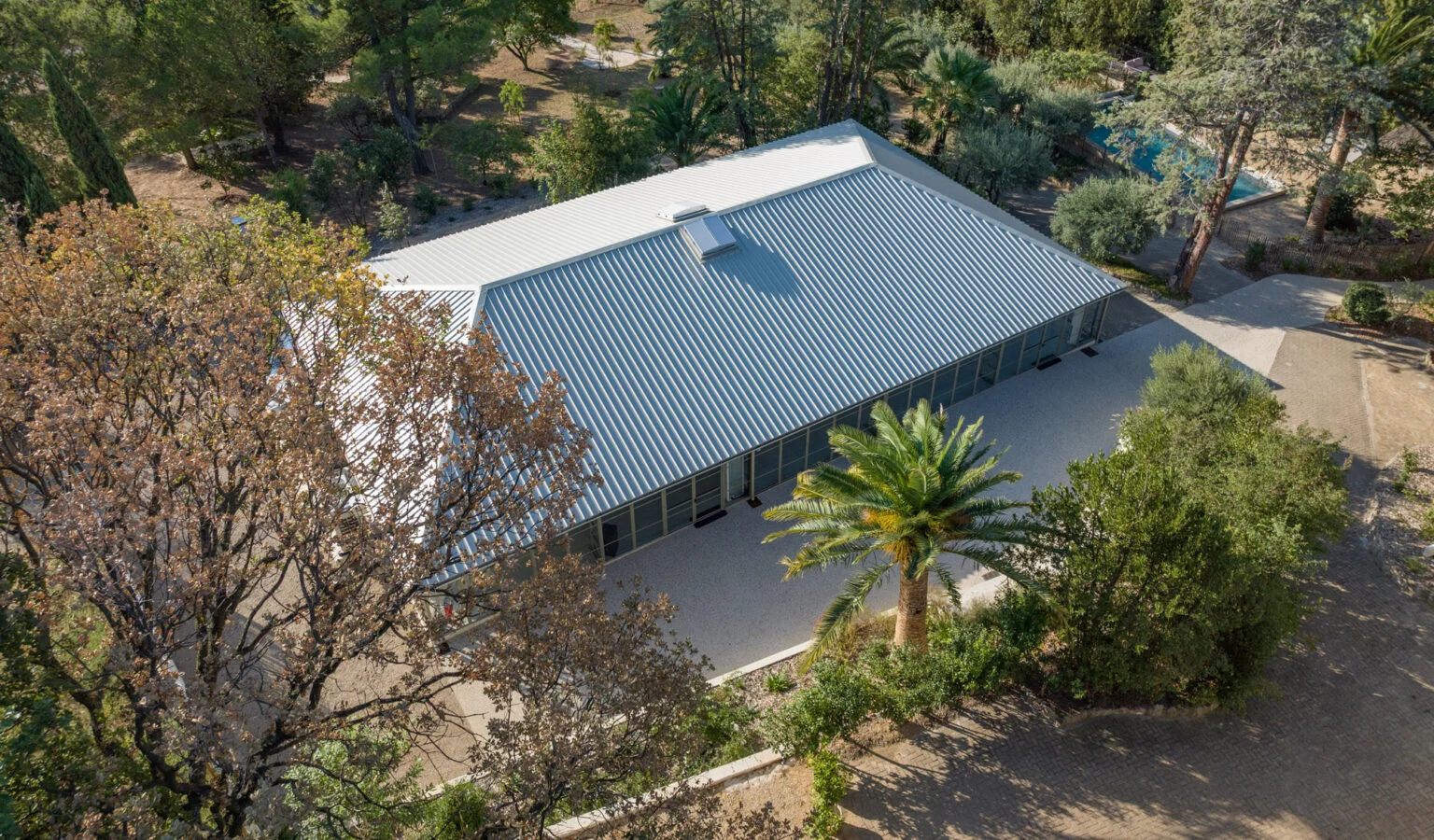 Vue aérienne de la salle de réception du Mas Aubrilha avec toiture métallique blanche, domaine mariage Hérault
