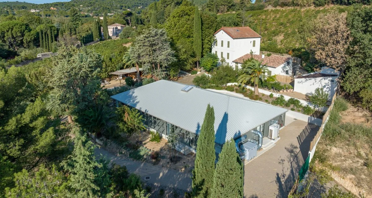 Vue aérienne du Mas Aubrilha en Hérault avec sa salle de réception vitrée et sa bastide provençale entourée de jardins
