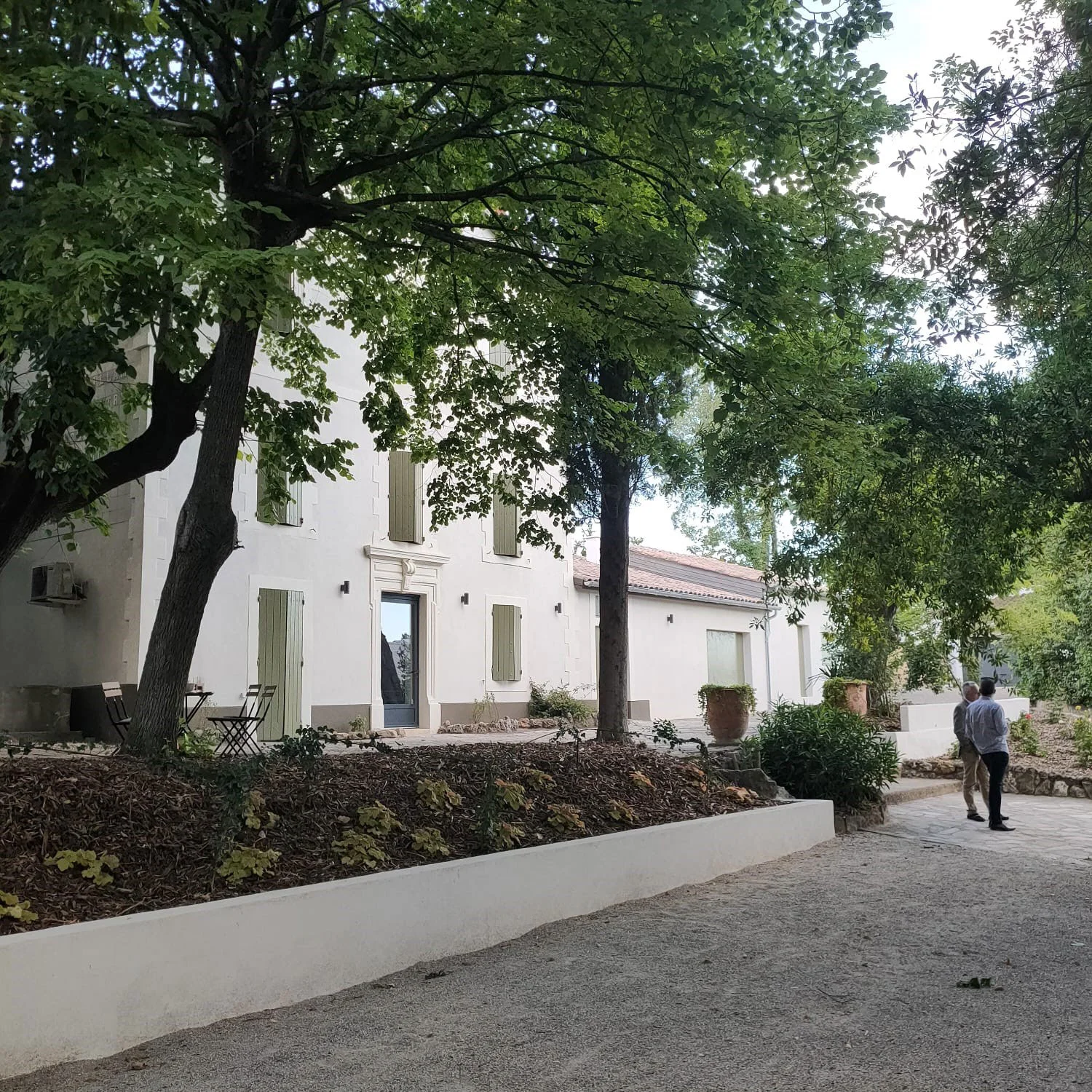 Vue d'ensemble du Mas Aubrilha, bâtiment blanc aux volets verts entouré de jardins, domaine mariage Hérault