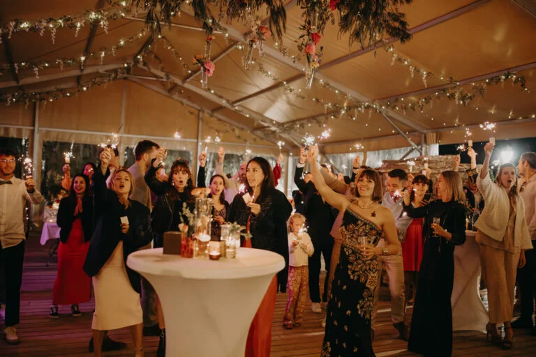 Tente de réception mariage Mas de Baumes décorée guirlandes lumineuses et fleurs en Hérault avec invités festifs