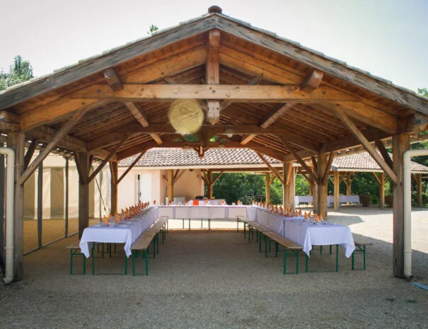 Grande halle en bois avec tables dressées en U pour un repas de mariage au Mas de Pradines, Hérault