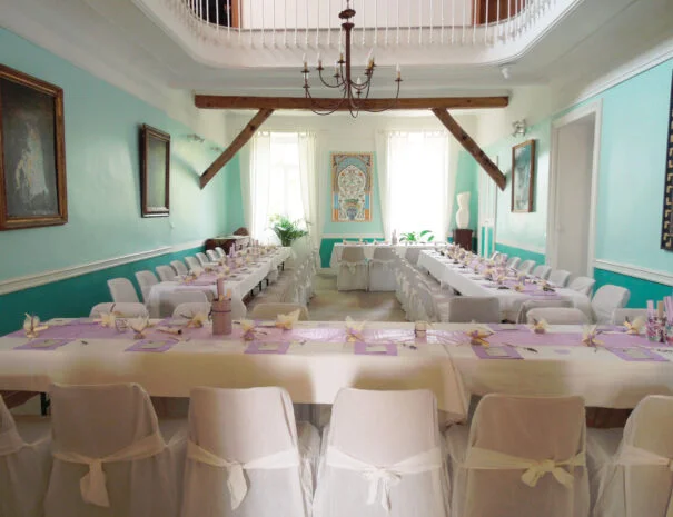 Salle de réception intérieure turquoise avec tables en U dressées pour mariage au Mas de Pradines, Hérault