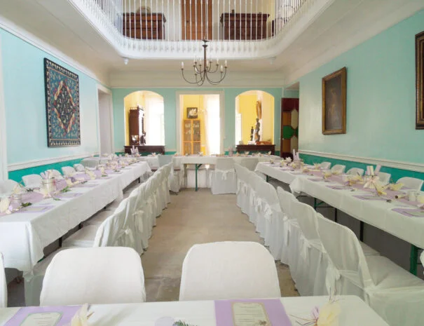 Vue intérieure de la salle de réception du Mas de Pradines avec tables longues dressées et arches décoratives, mariage Hérault